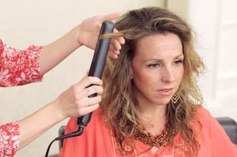 Stylist and client using a flat iron to get curls