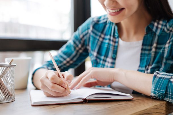 woman sitting at desk writing in a notebook