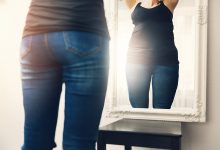 rear view of woman's torso as she looks in the mirror