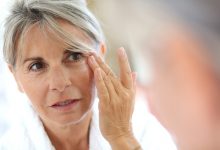 gray haired woman looking in mirror