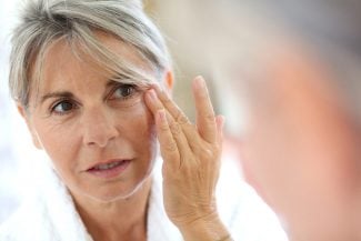 gray haired woman looking in mirror