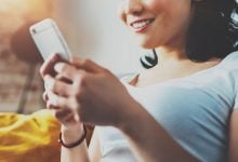 woman smiling while she texts on her phone