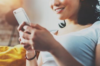woman smiling while she texts on her phone