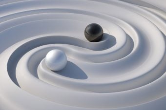 Artistic interpretation of the yin/yang symbol with black and white balls on a fluid white surface