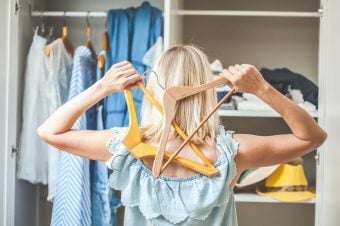 Woman looking into her closet holding hangers