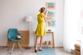 Woman in yellow dress straightening photos on a wall