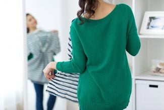 Woman in green sweater looking in mirror