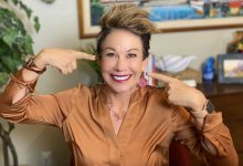 Carol smiling pointing to her face