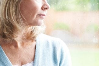 Woman in blue shirt looking out the window as it rains