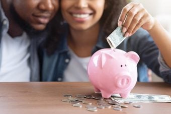 What's Your Money Type? Black couple smiling putting money in a pink piggy bank