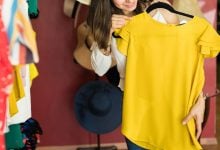 Woman holding up yellow shirt in store