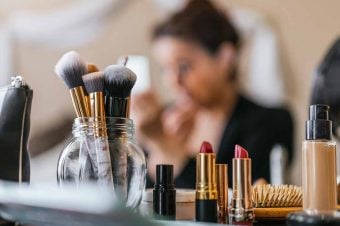 Woman putting on makeup with all her products in front