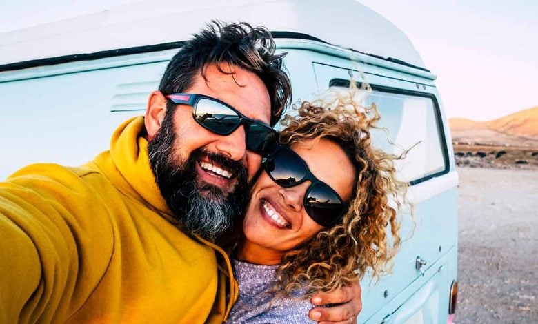 Middle age couple smiling while taking a selfie by their camper